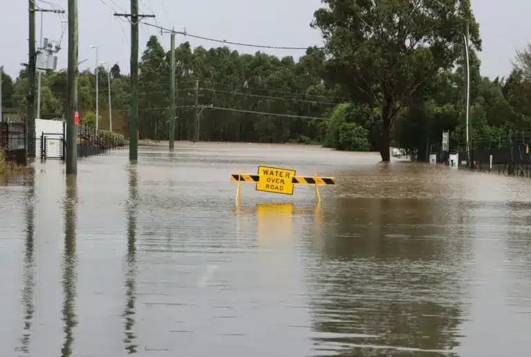 A flooded road with a warning sign under water