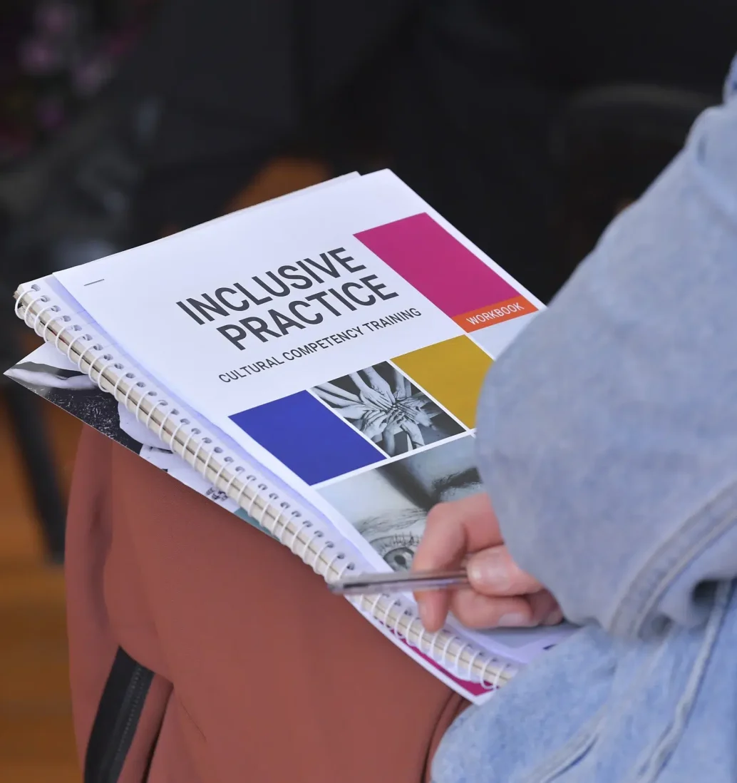 Person holding inclusive practice training workbook.