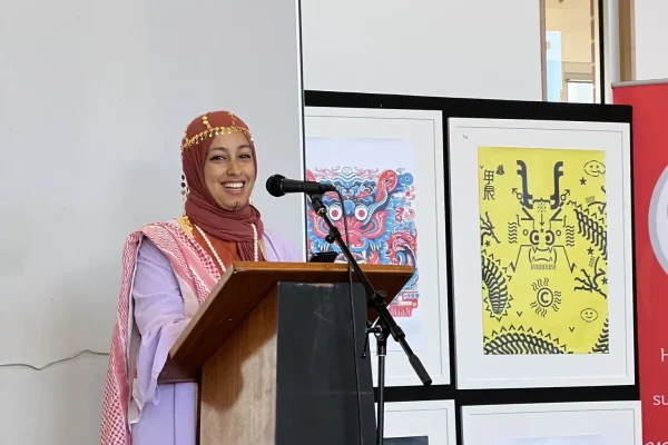 Woman in colourful attire speaks at podium.