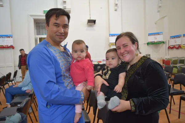 Family holding babies at cultural event indoors.