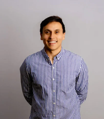 Smiling person wearing a striped shirt against grey background.