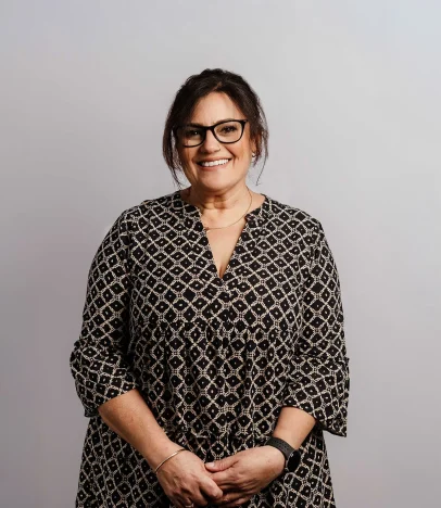 Smiling woman wearing glasses and patterned dress.
